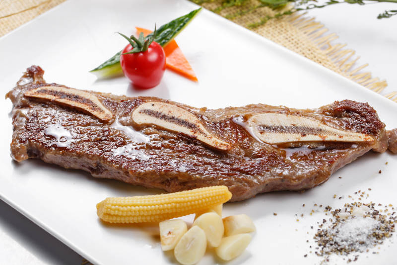 日式铁板带骨小牛排摆放在草垫上图片