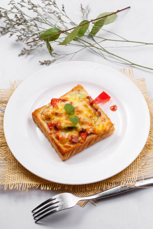 白色圆盘装现烤海鲜牛肉小披萨摆放在草垫上图片