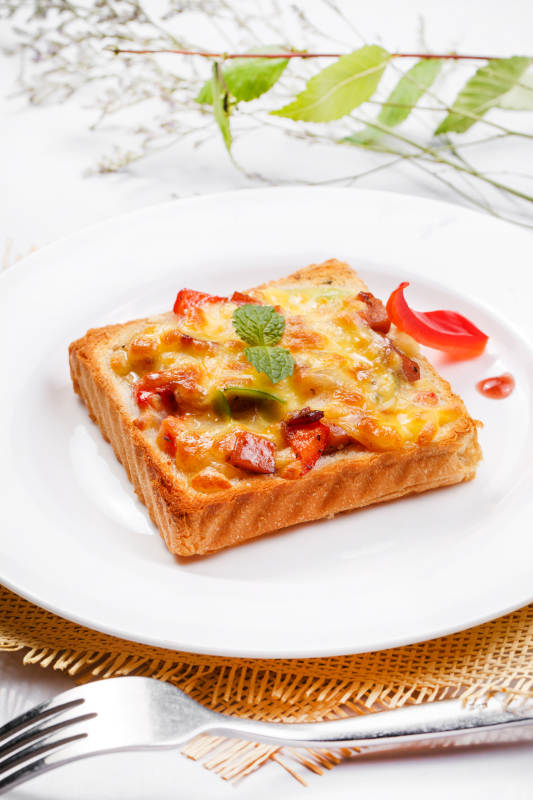 白色圆盘装现烤海鲜牛肉小披萨摆放在草垫上图片