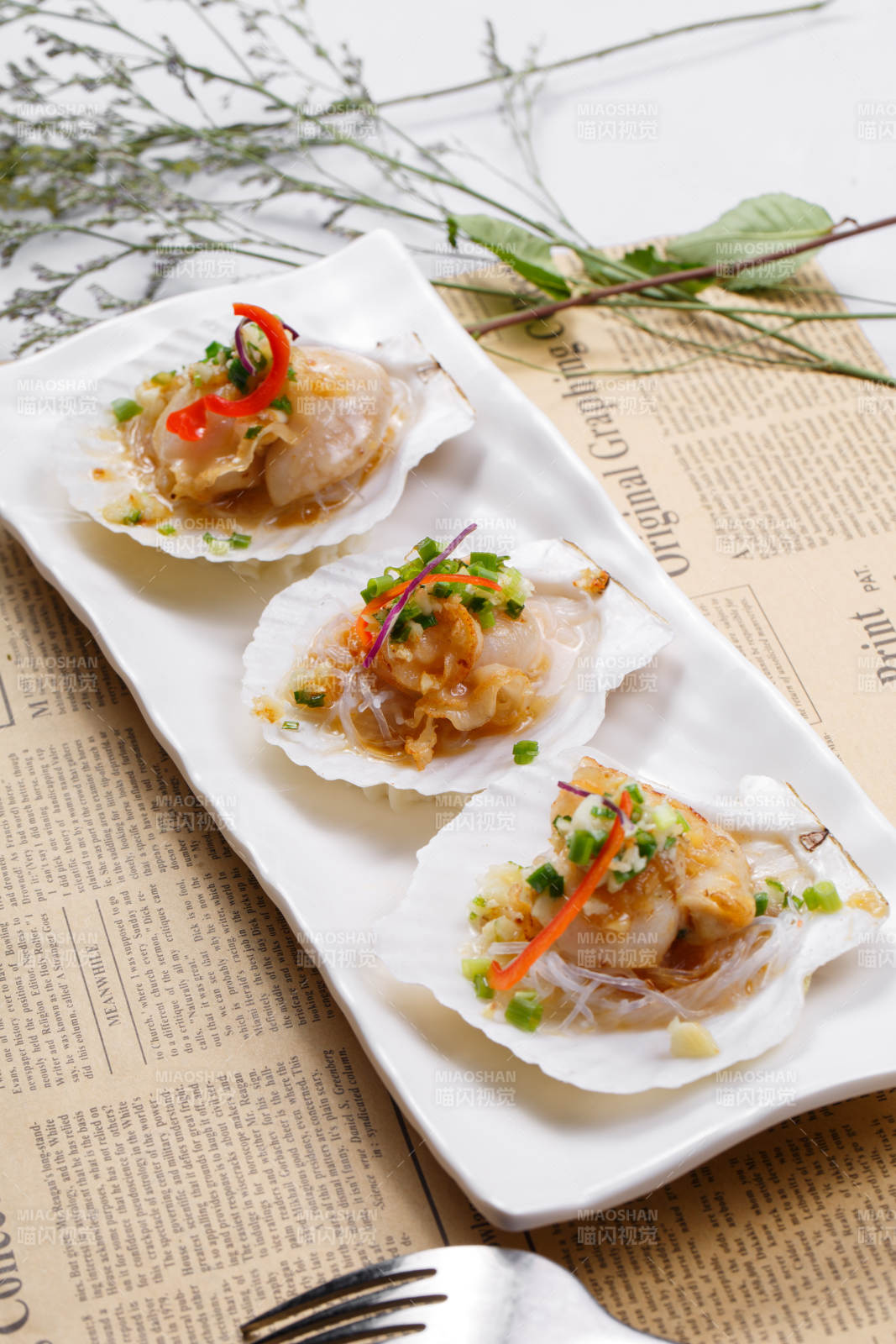 蒜蓉粉丝XO酱蒸扇贝摆放在英文包装纸上图片