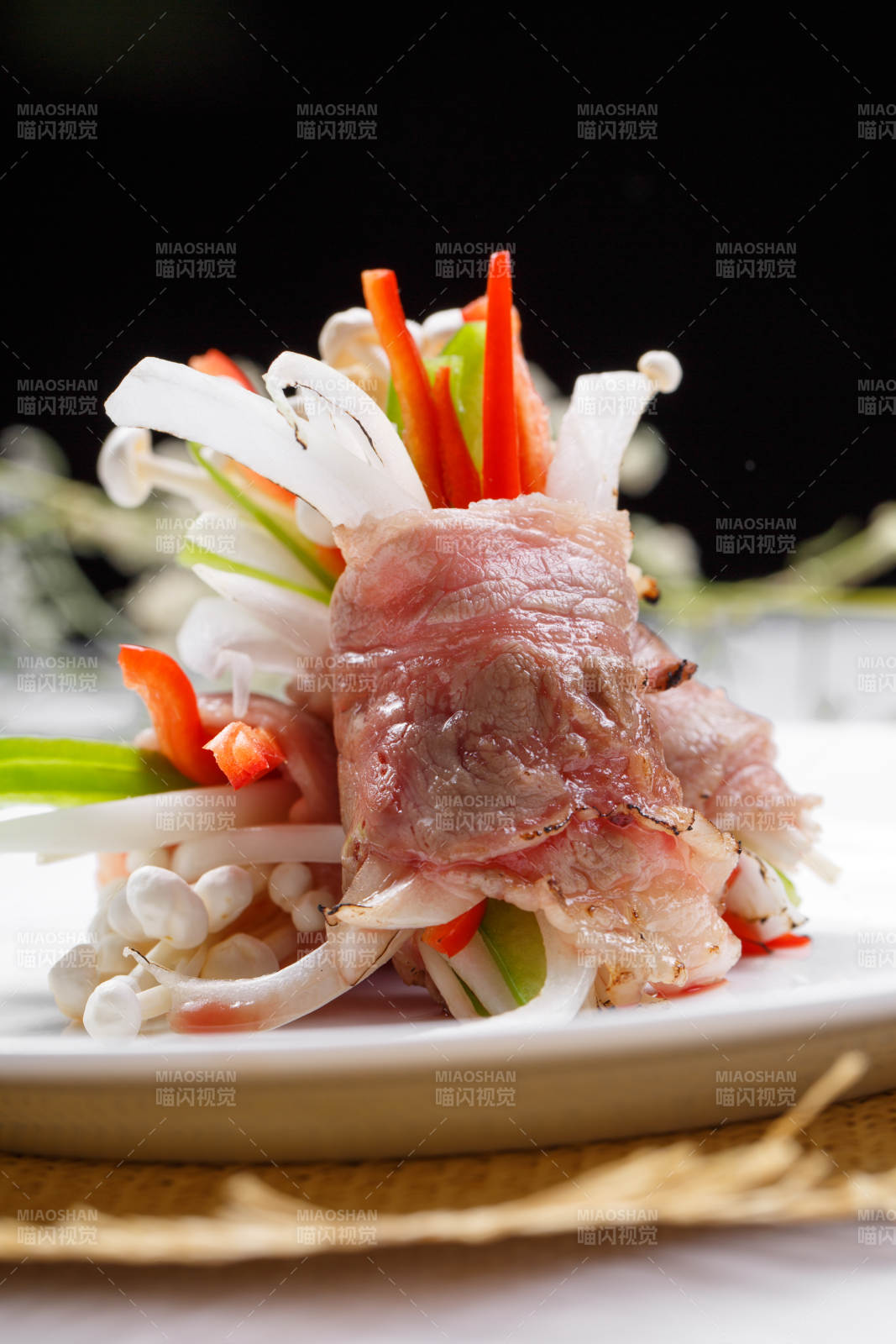 白色圆盘装的法式鹅肝牛肉卷摆放在草垫上图片