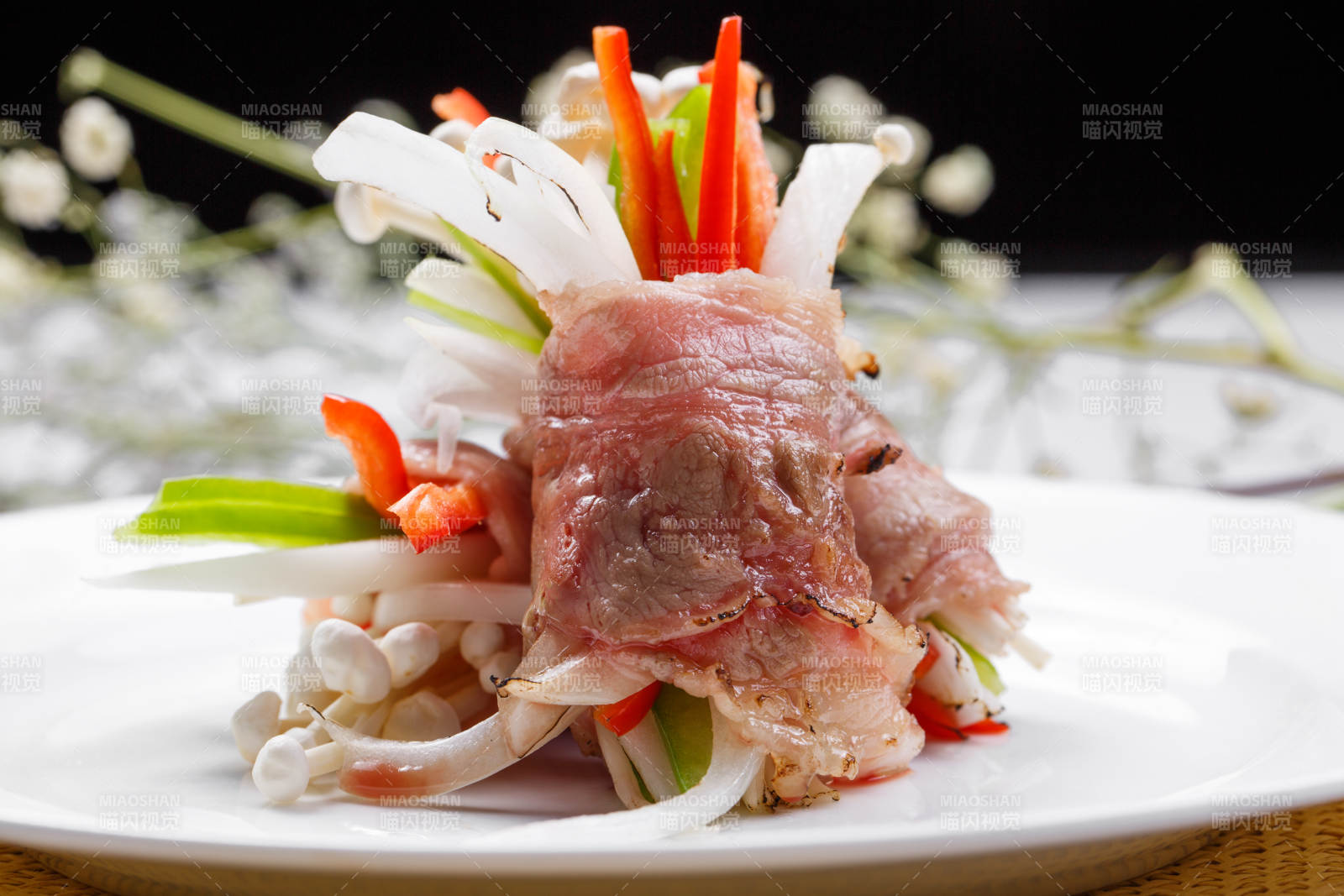 白色圆盘装的法式鹅肝牛肉卷摆放在草垫上图片