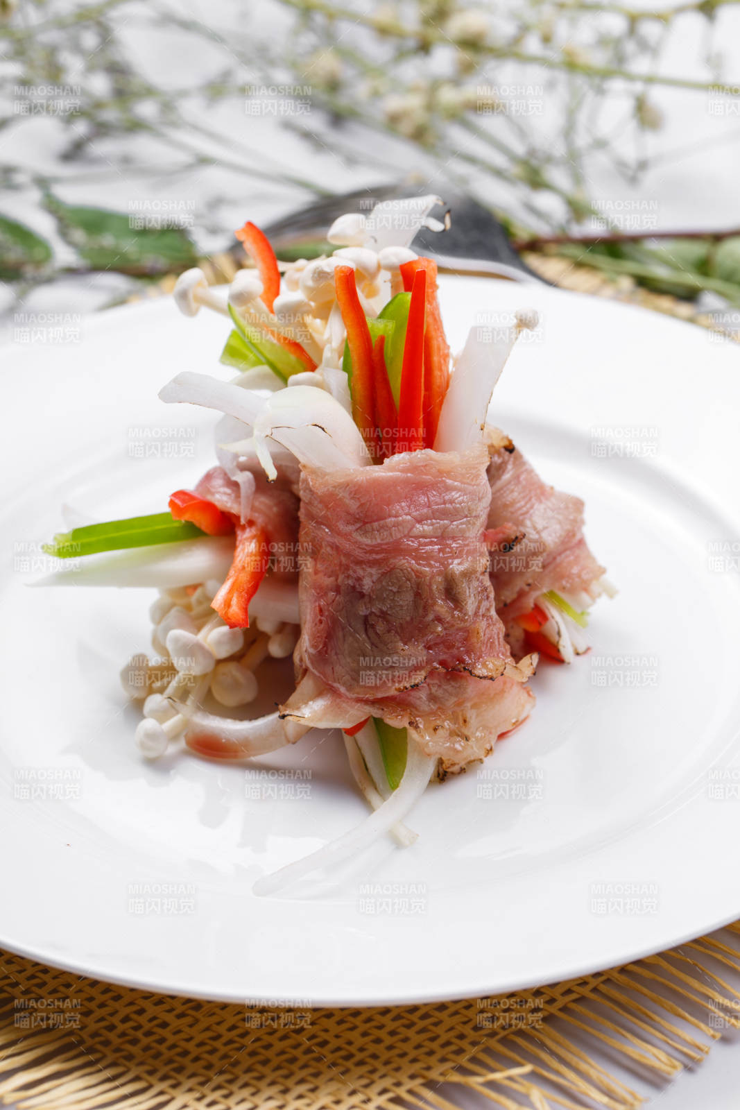 白色圆盘装的法式鹅肝牛肉卷摆放在草垫上图片