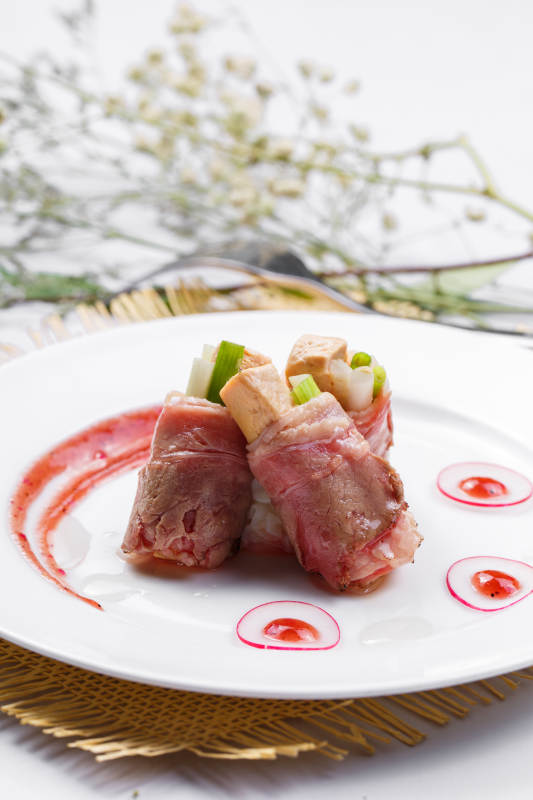 白色圆盘装的法式鹅肝牛肉卷摆放在草垫上图片