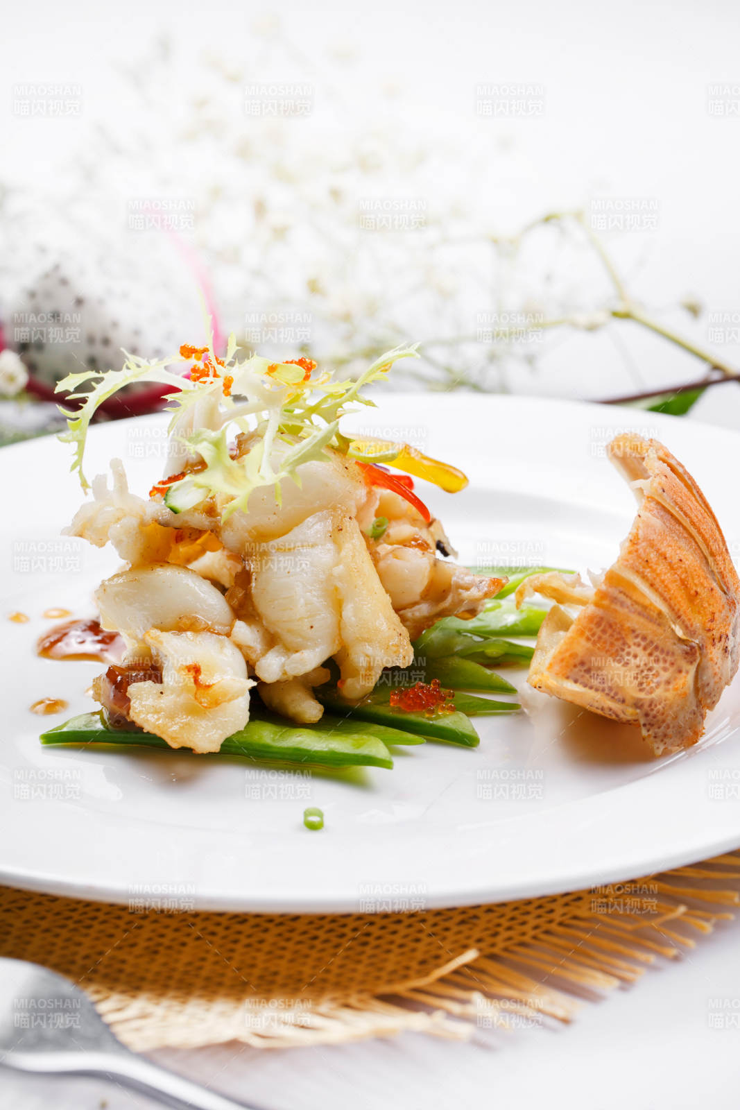 香辣铁板煎龙虾尾肉摆放在草垫上图片