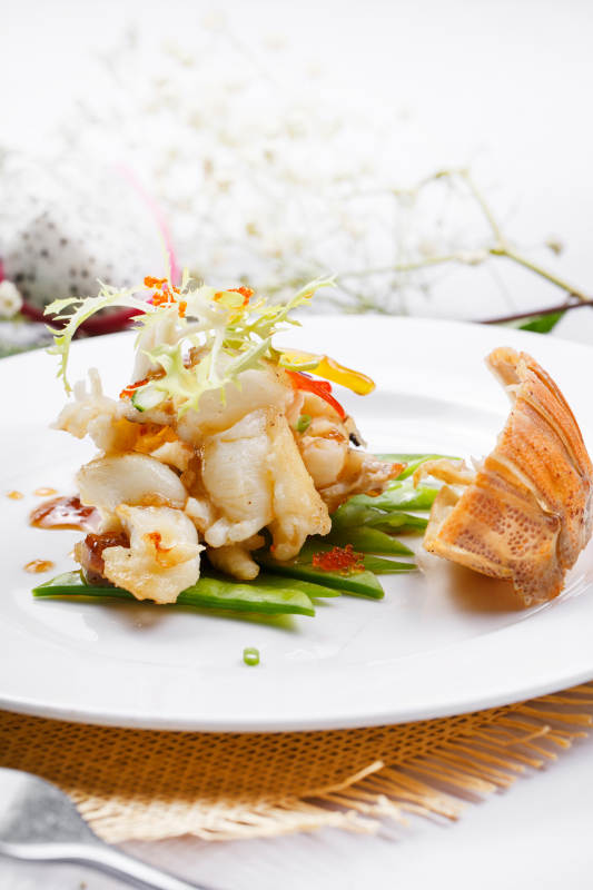 香辣铁板煎龙虾尾肉摆放在草垫上图片