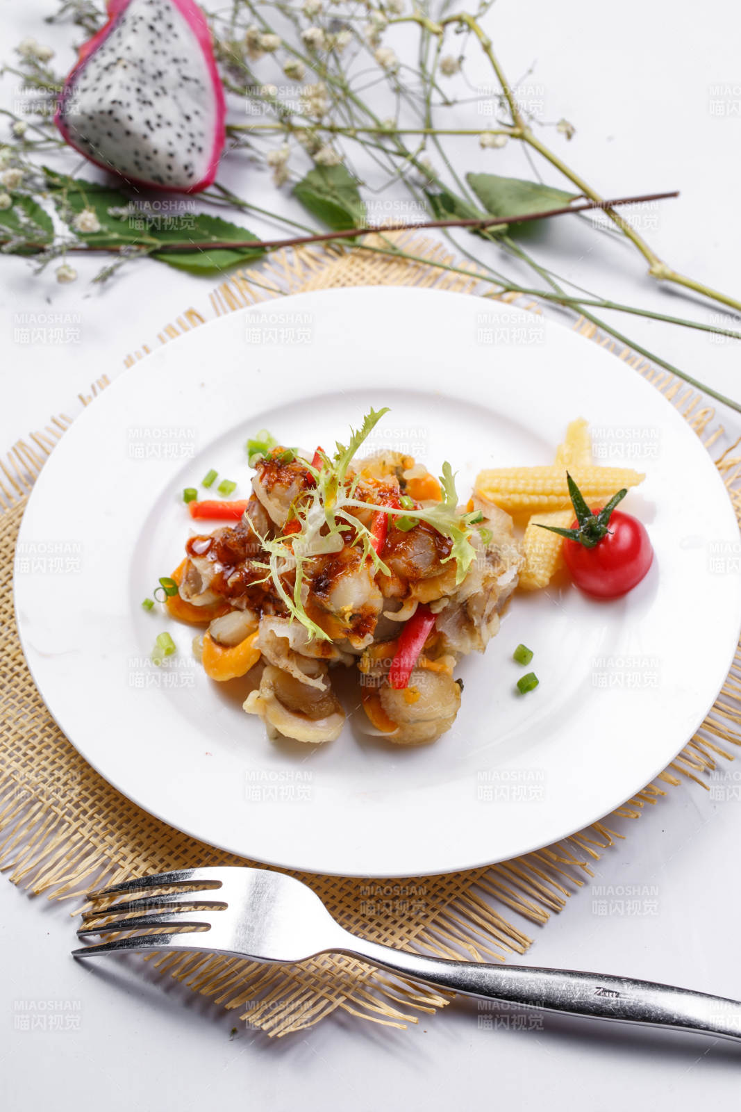 白色瓷盘装的铁板香辣扇贝肉摆放在草垫上图片