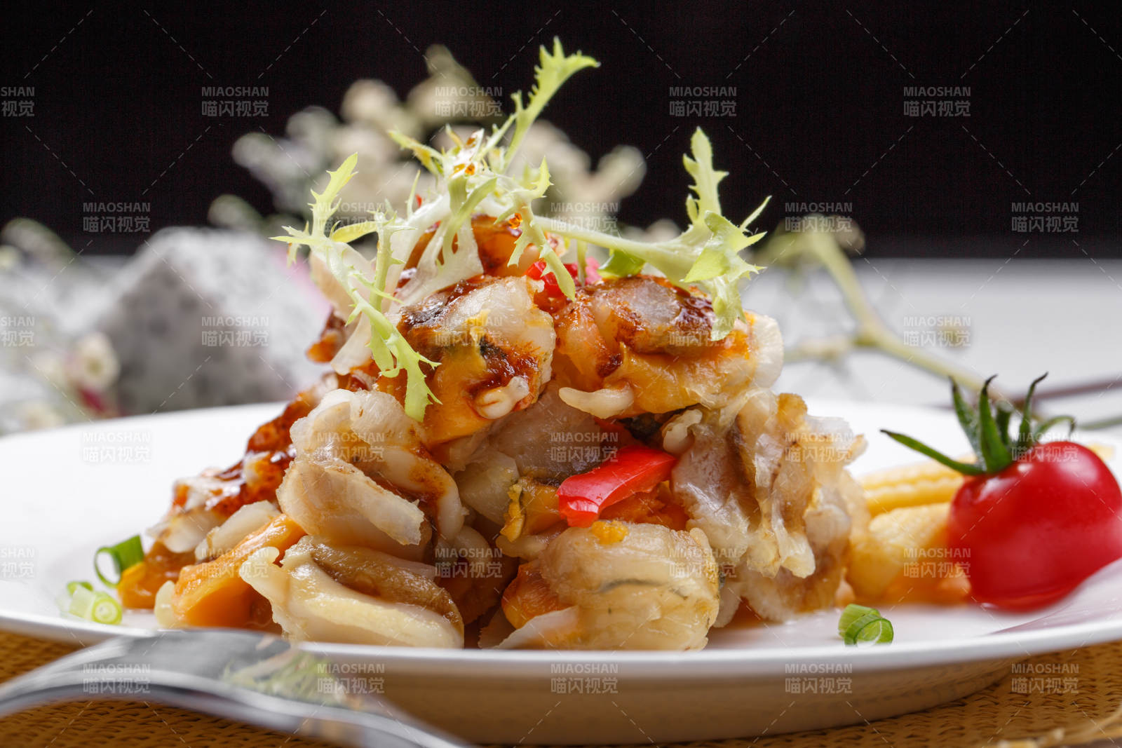 白色瓷盘装的铁板香辣扇贝肉摆放在草垫上图片