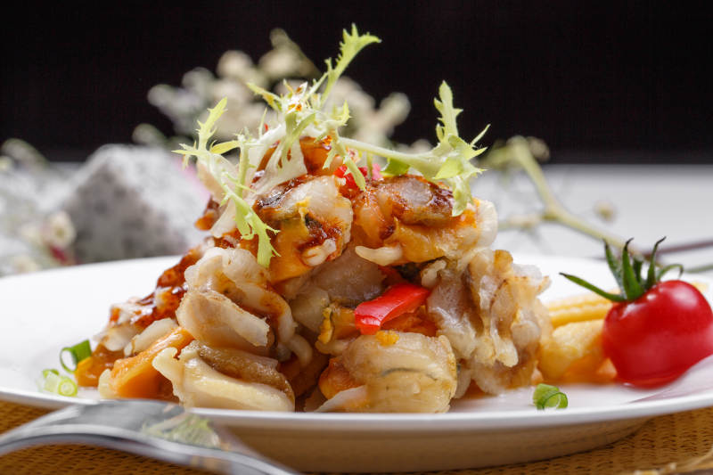 白色瓷盘装的铁板香辣扇贝肉摆放在草垫上图片