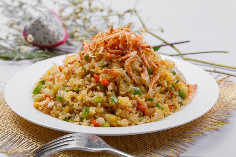 铁板虾干蛋炒饭摆放在草垫上图片
