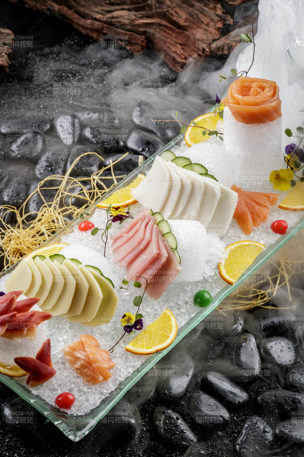 刺身拼摆放在干冰缭绕的黑色鹅卵石上图片