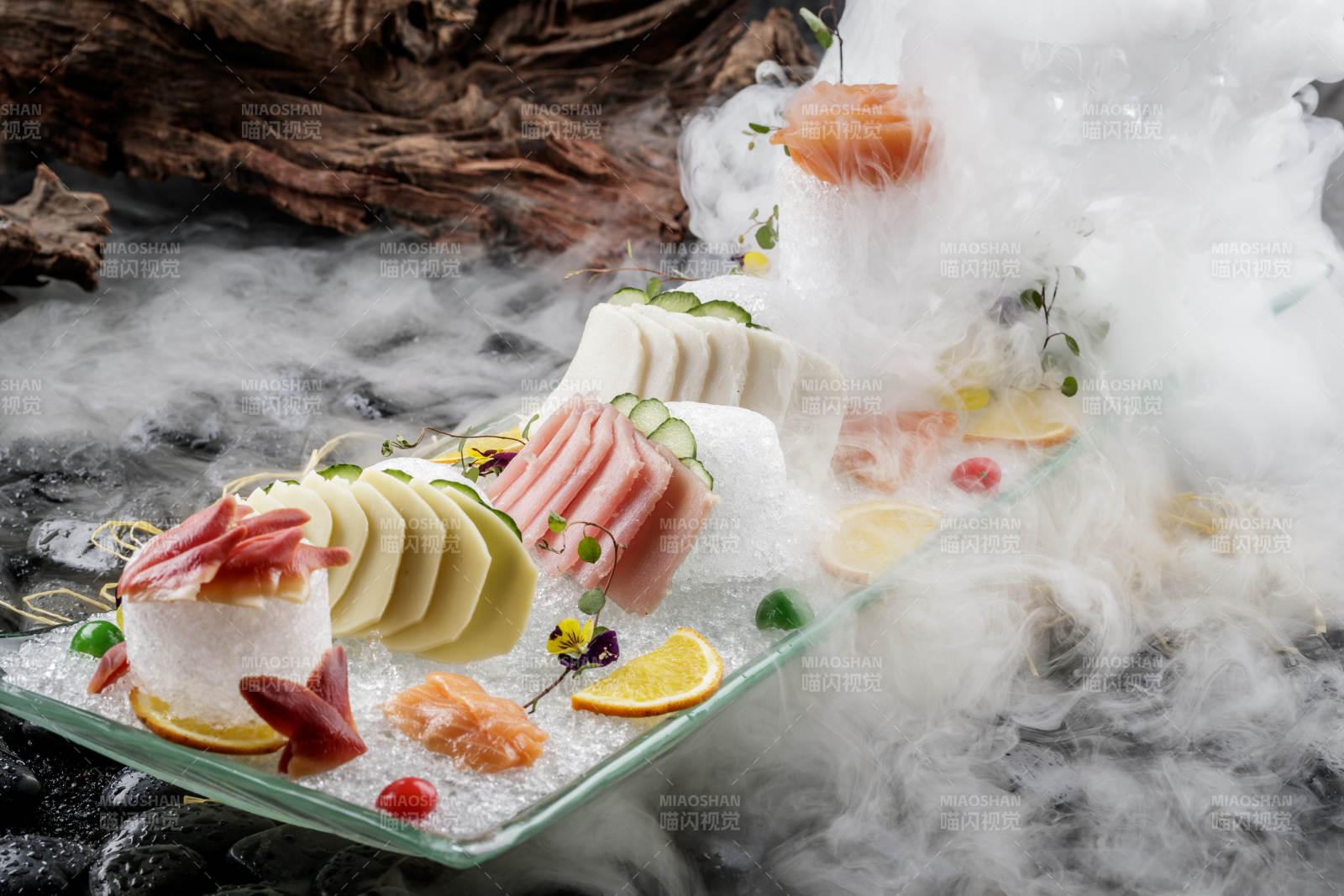 刺身拼摆放在干冰缭绕的黑色鹅卵石上图片