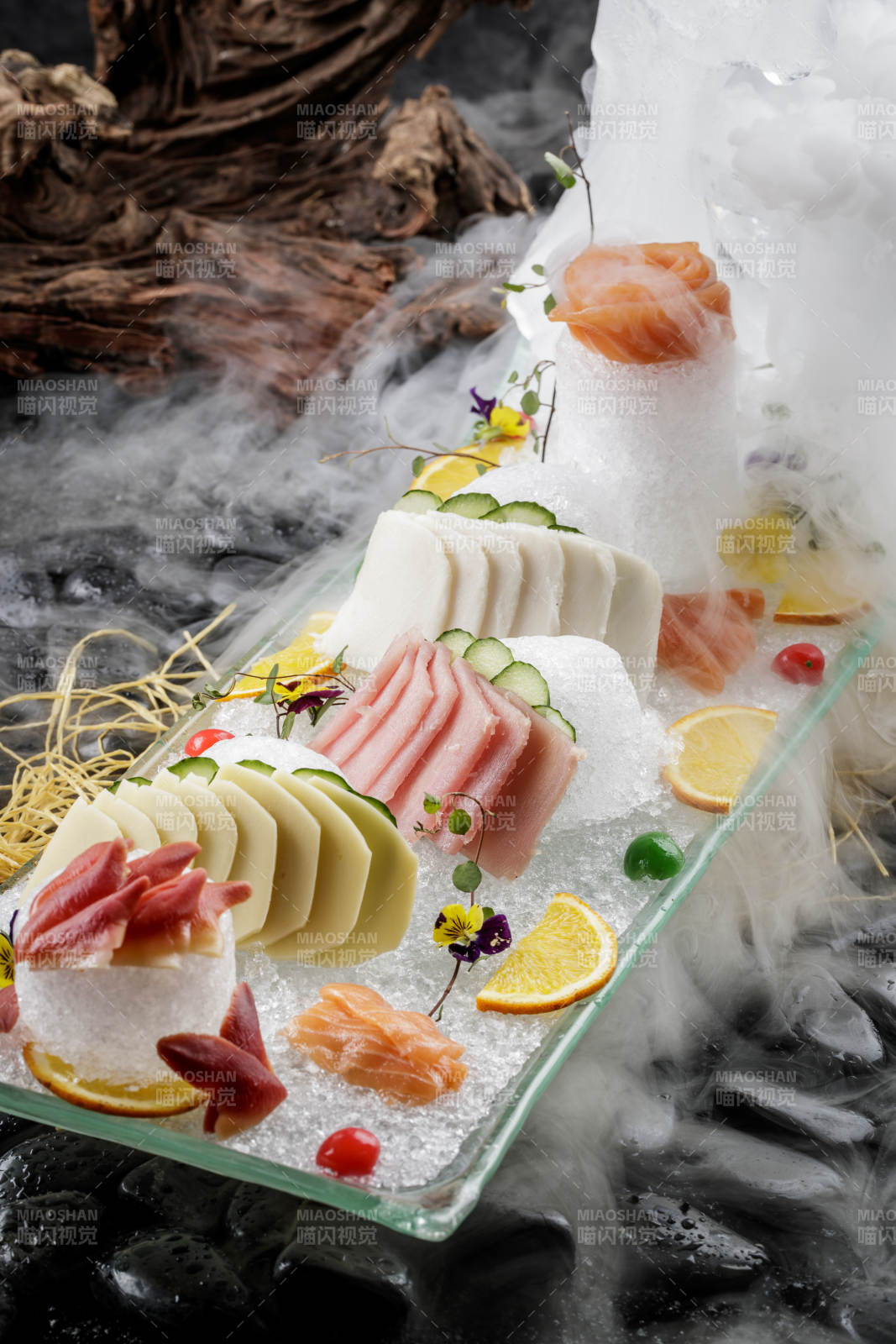 刺身拼摆放在干冰缭绕的黑色鹅卵石上图片