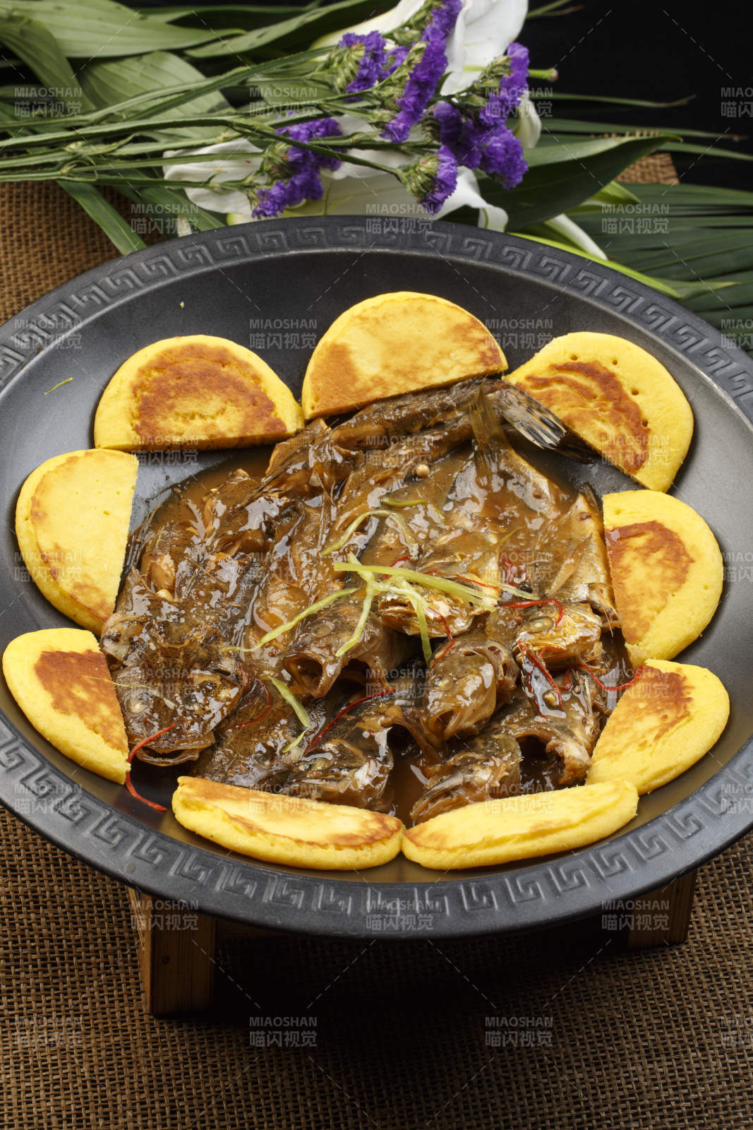 黑色铁锅装的垮炖海鲜杂鱼贴饼子图片