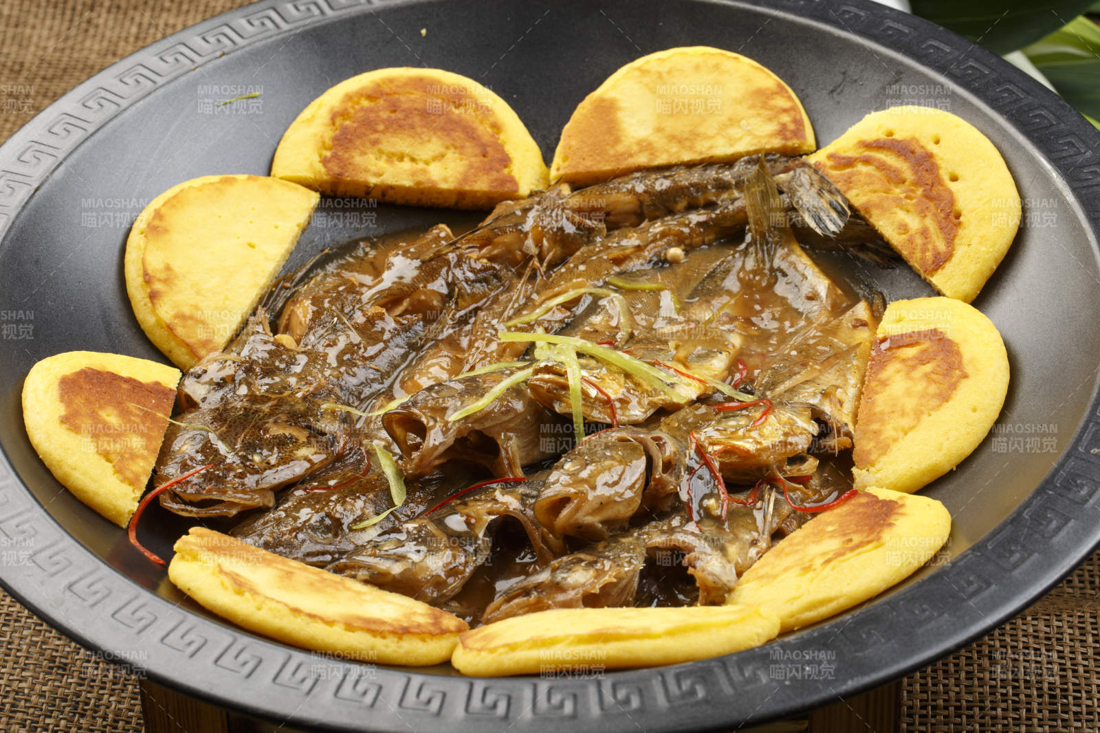 黑色铁锅装的垮炖海鲜杂鱼贴饼子图片