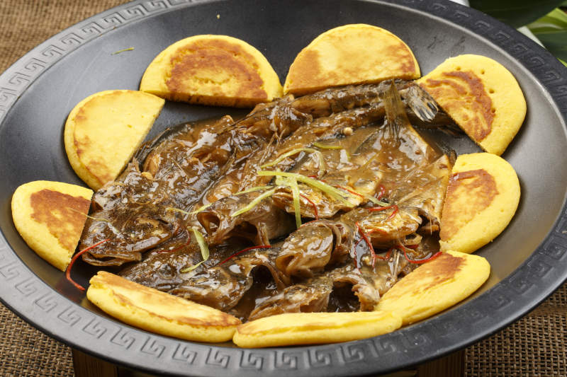 黑色铁锅装的垮炖海鲜杂鱼贴饼子图片