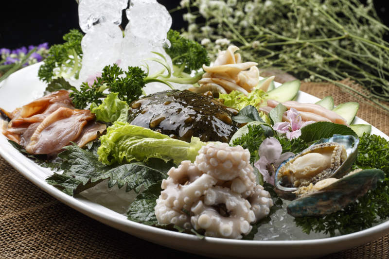 椭圆形白瓷盘装的胶东海鲜刺身拼盘图片