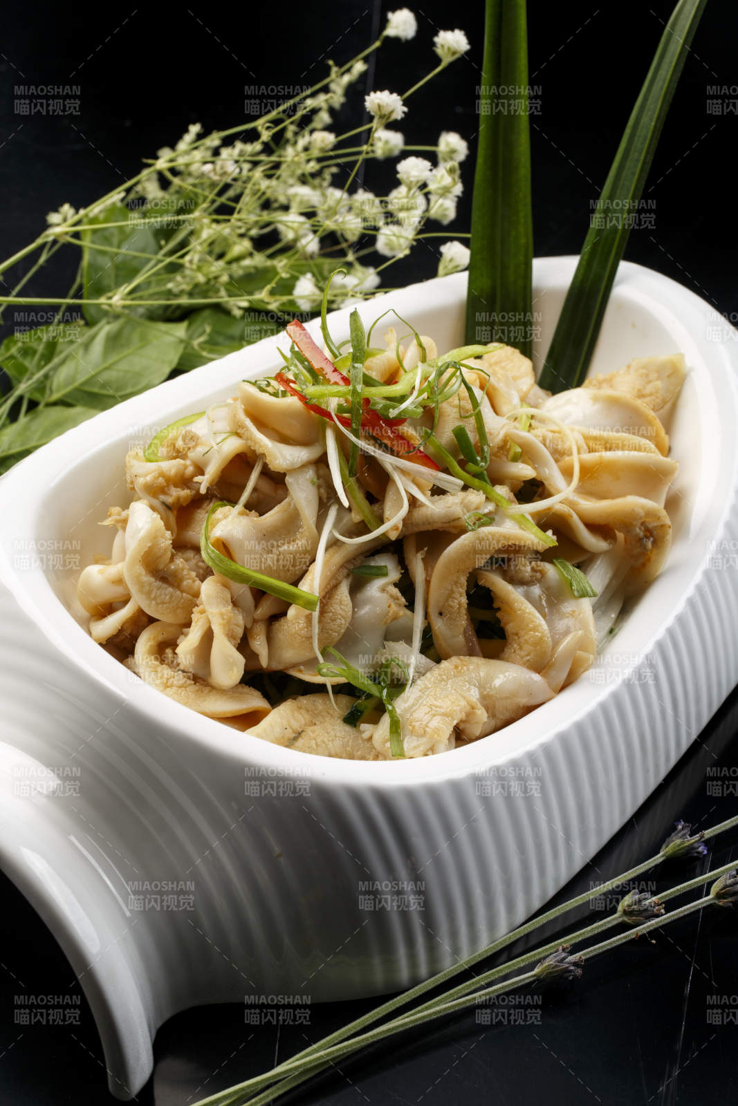 水平形瓷盘装的温拌海螺头图片