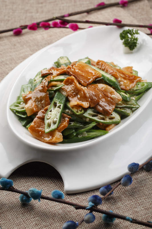 白色瓷餐具装的鲜秋葵炒五花肉图片