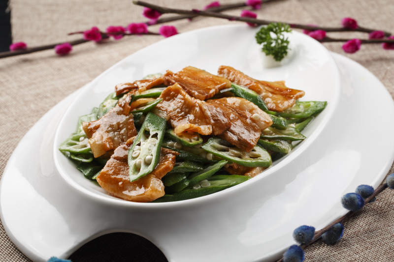 白色瓷餐具装的鲜秋葵炒五花肉图片