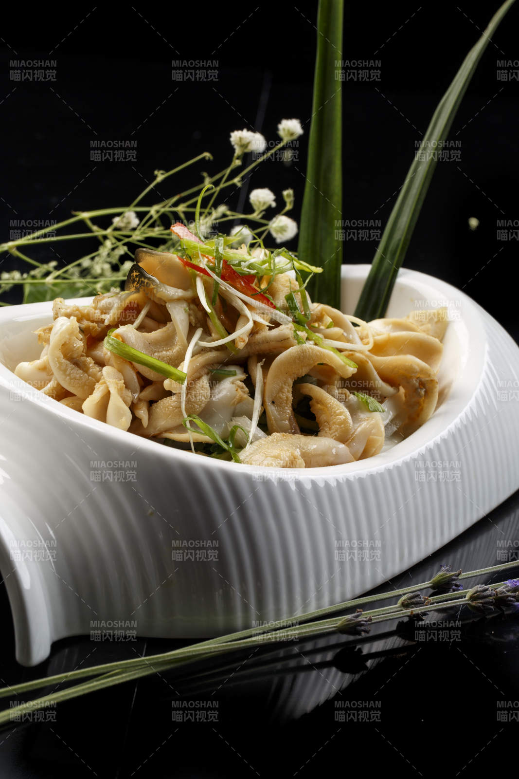 水平形瓷盘装的温拌海螺头图片