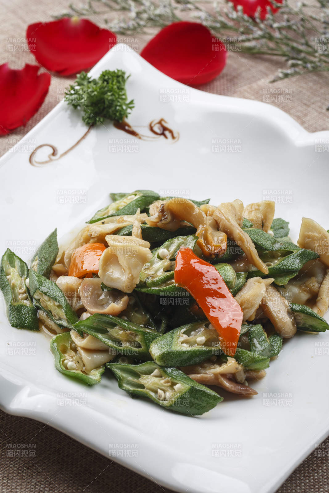 方形浪花边白瓷盘装的海鲜秋葵炒大海螺肉图片