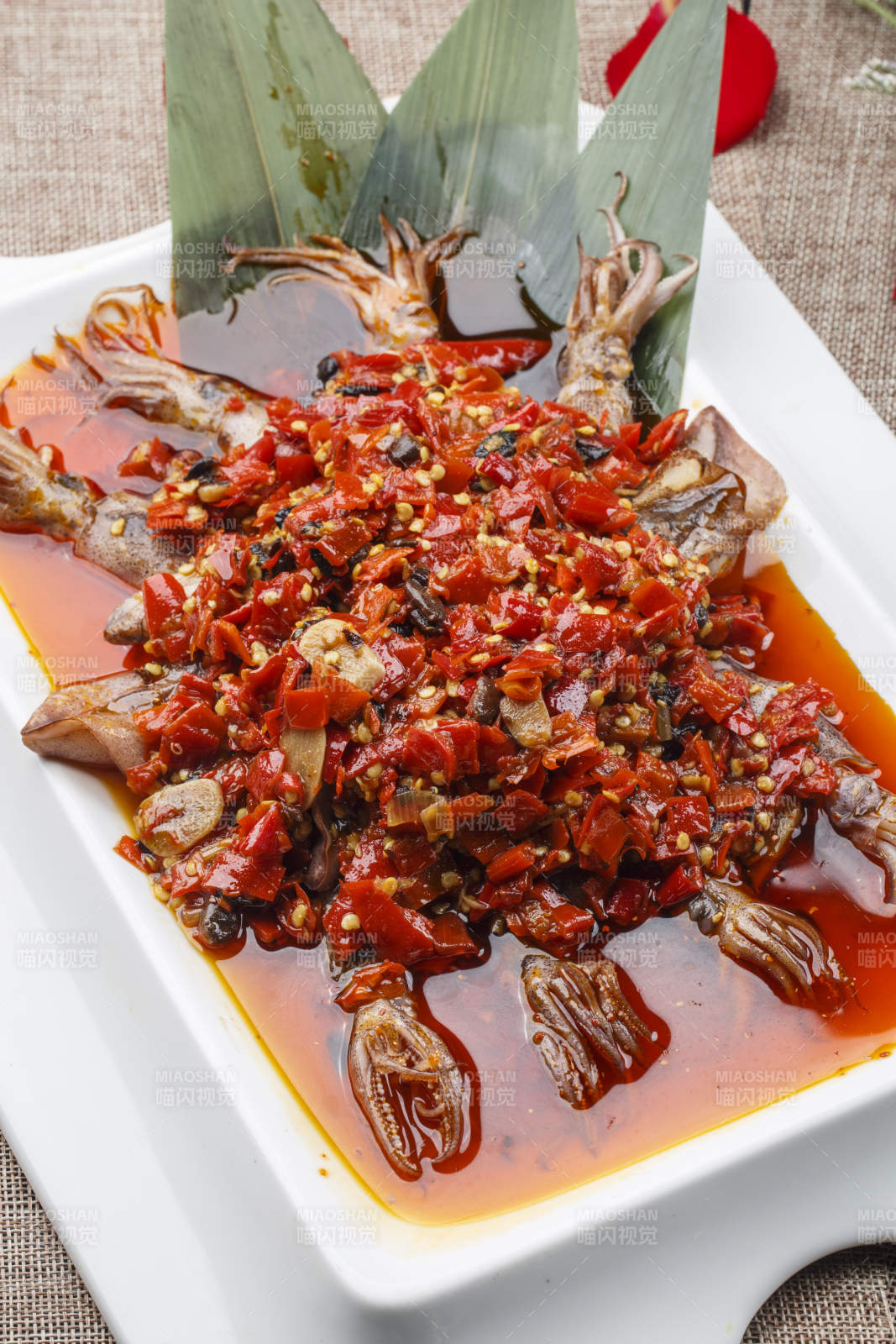 白色长方形瓷盘装的豆瓣酱香辣红油炒海鲜小管图片