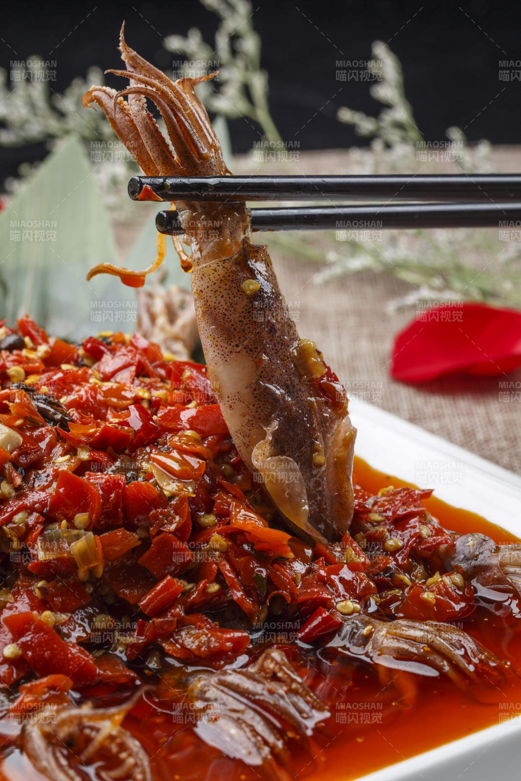 白色长方形瓷盘装的豆瓣酱香辣红油炒海鲜小管图片