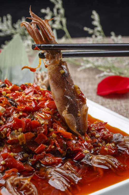 白色长方形瓷盘装的豆瓣酱香辣红油炒海鲜小管图片