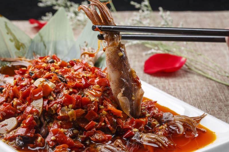 白色长方形瓷盘装的豆瓣酱香辣红油炒海鲜小管图片