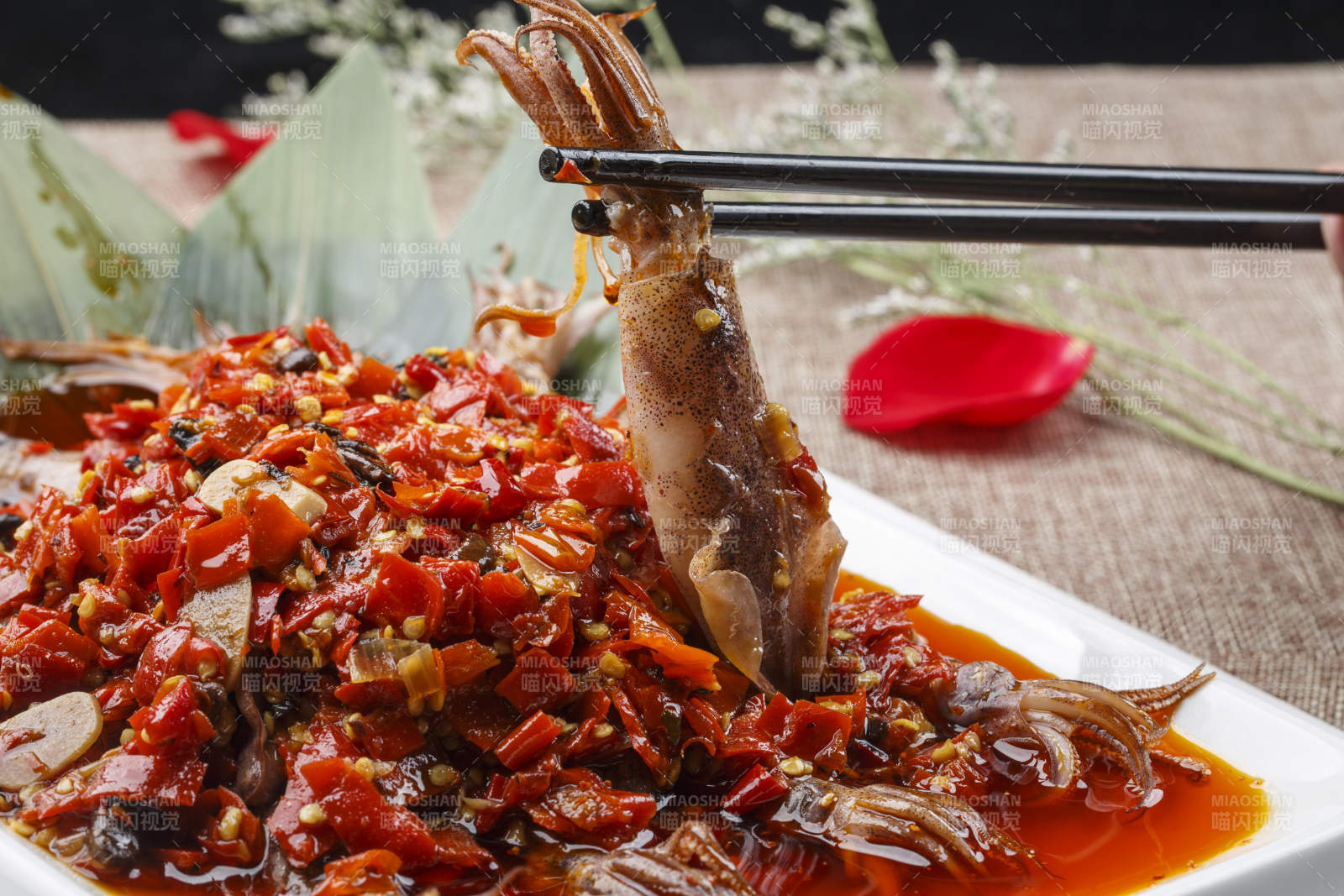白色长方形瓷盘装的豆瓣酱香辣红油炒海鲜小管图片
