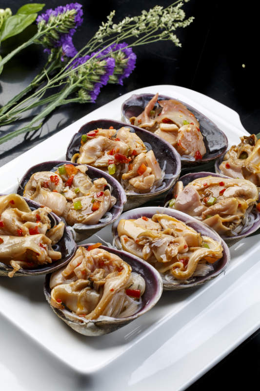 鼎形瓷盘装的海鲜炭烤紫石房蛤天鹅蛋图片