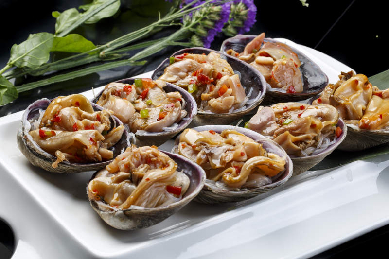 鼎形瓷盘装的海鲜炭烤紫石房蛤天鹅蛋图片