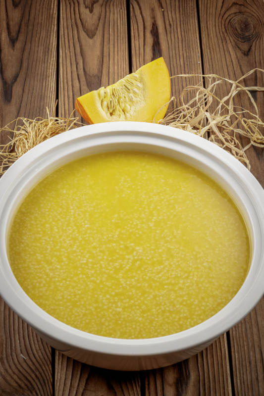 白色汤盆装的金瓜小米粥图片