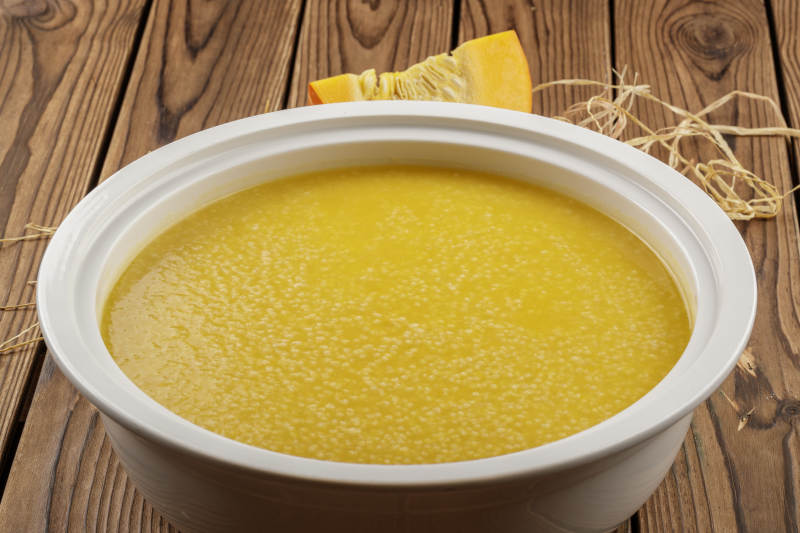 白色汤盆装的金瓜小米粥图片