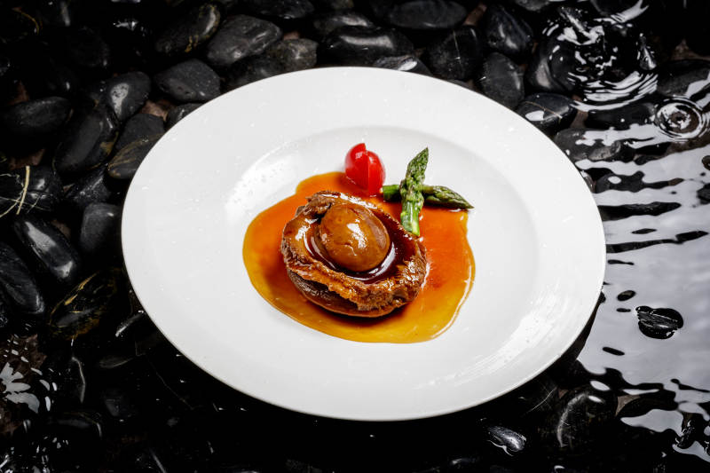 白色瓷盘装的浇汁南非干鲍图片