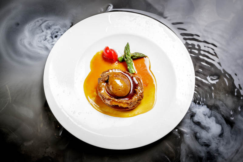 白色瓷盘装的浇汁南非干鲍图片