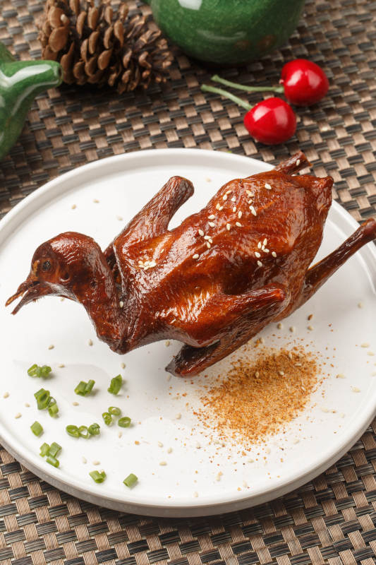 白色圆瓷盘装的港式脆皮鸡摆放在餐垫上图片