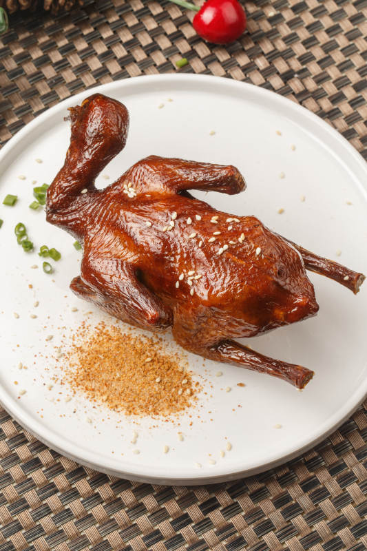 圆形白瓷盘装的港式脆皮乳鸽摆放在餐垫上图片