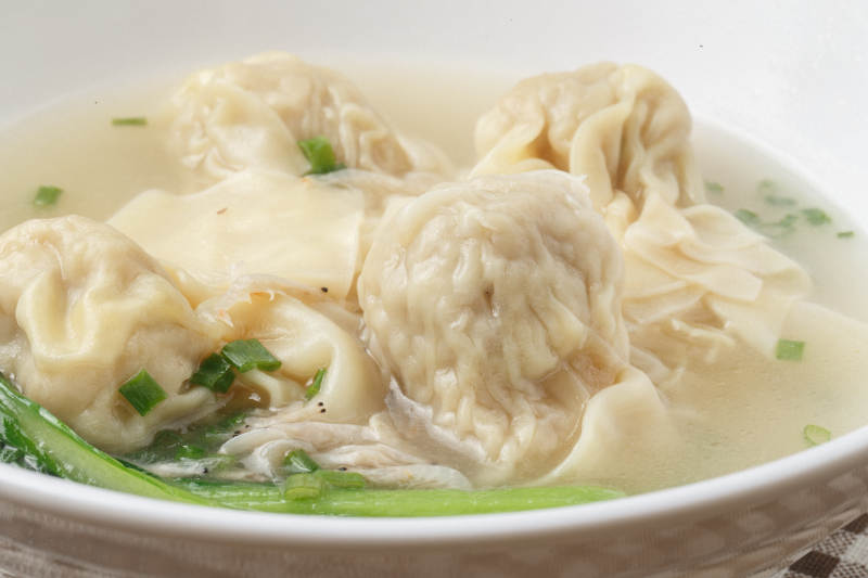 白色瓷碗装的云吞摆放在餐垫上图片