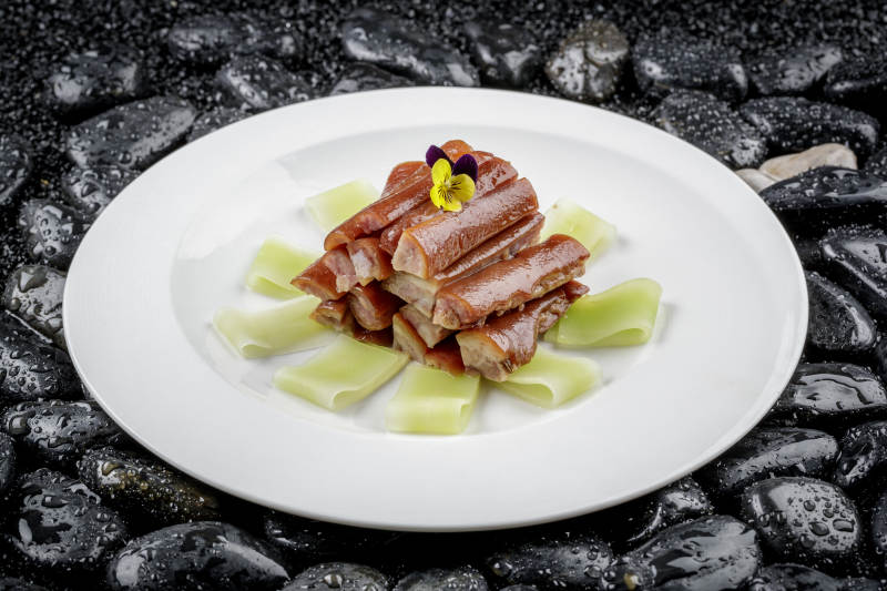 馋嘴猪尾摆放在黑色鹅卵石上图片