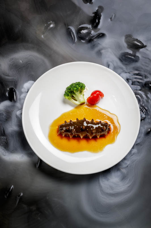 鲍汁扣辽参摆放在干冰缭绕的水中图片