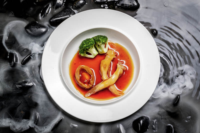 鲍汁鲍鱼烩花胶摆放在干冰缭绕的水中图片