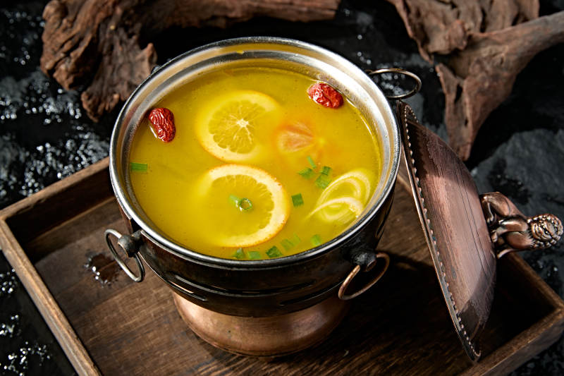 精致小火锅装的橙味鸡汤锅底图片