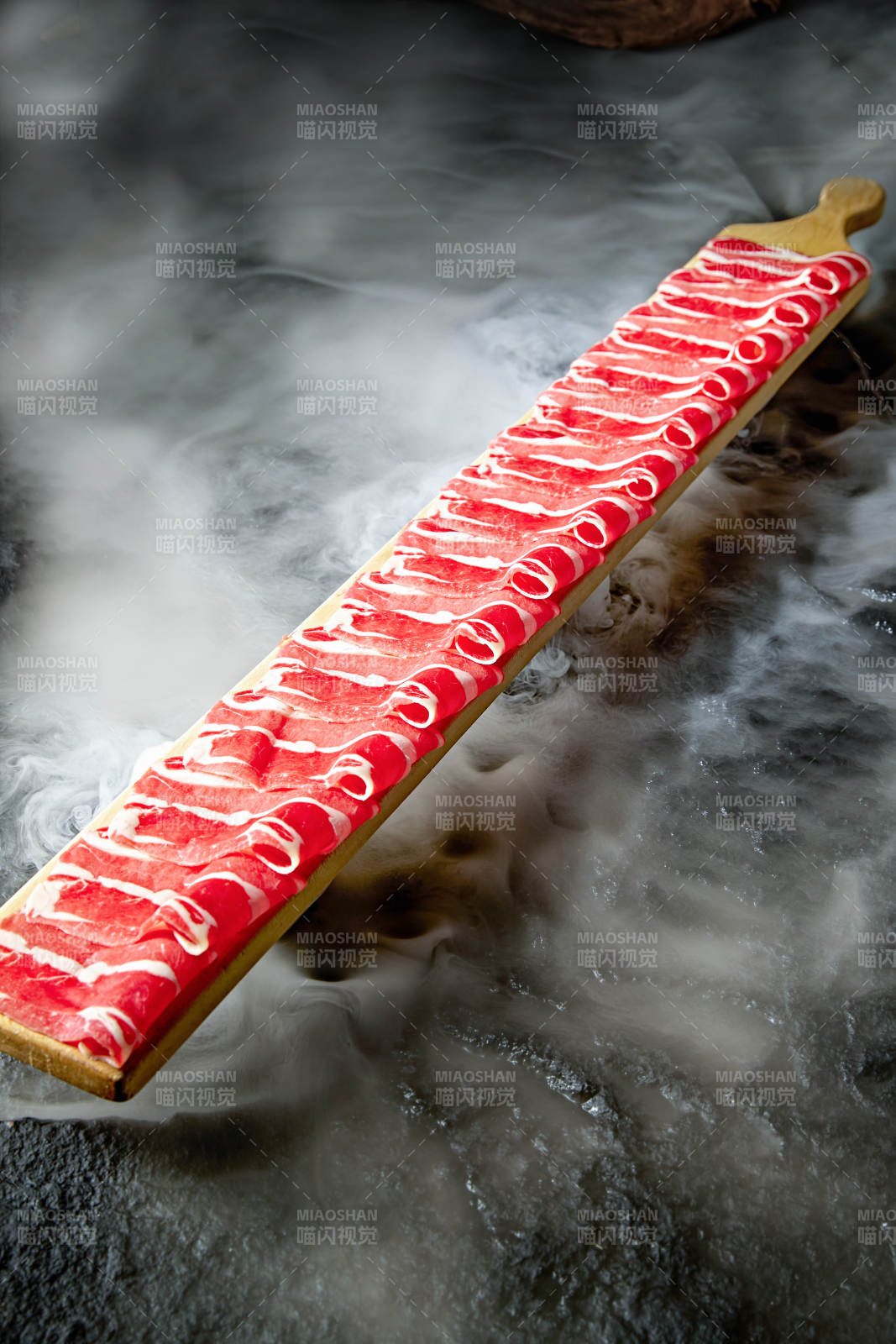 干冰缭绕的背景上摆放的和牛一米肉片图片
