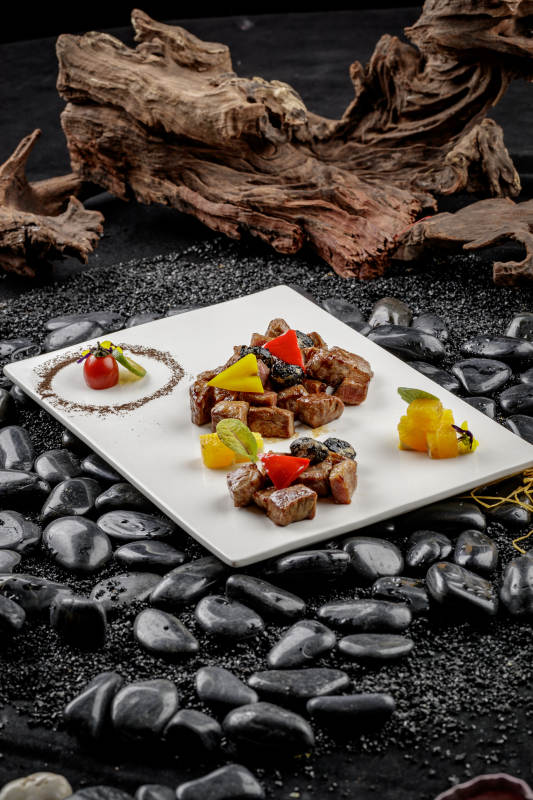 黑蒜牛小排摆放在黑色鹅卵石上图片