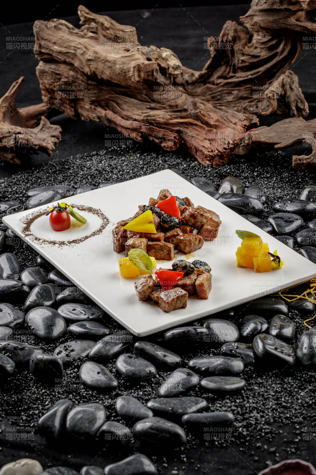 黑蒜牛小排摆放在黑色鹅卵石上图片