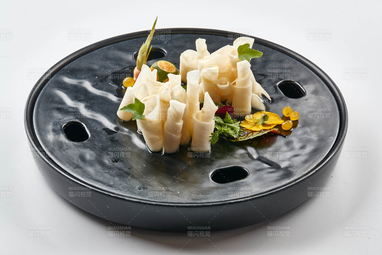 黑色瓷餐具装的鲜杏鲍菇刺身卷图片