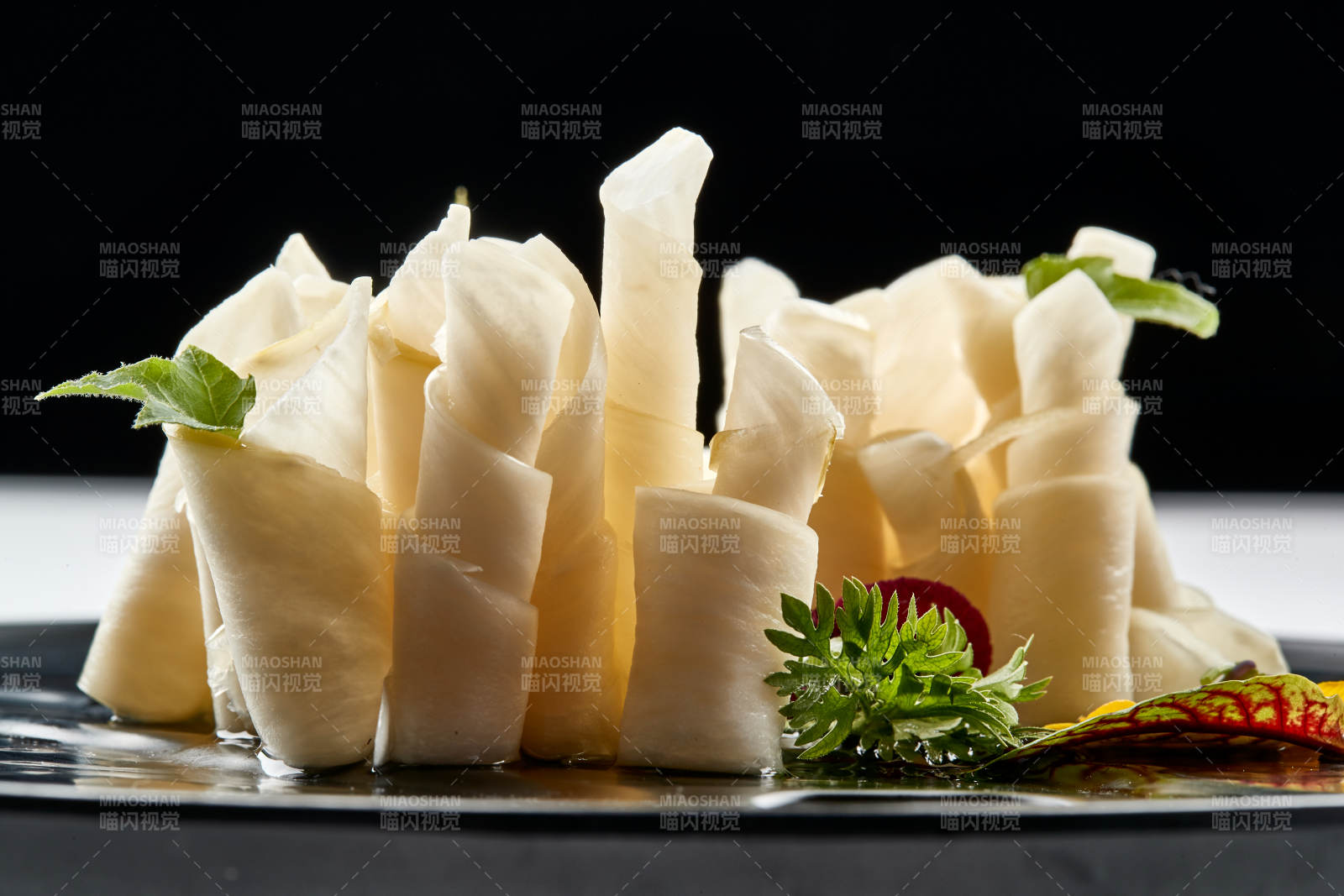 黑色瓷餐具装的鲜杏鲍菇刺身卷图片