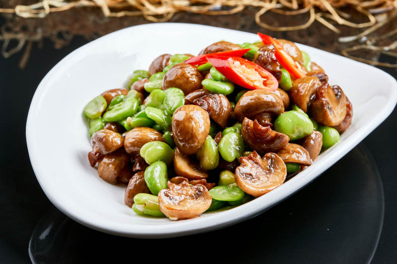 白色瓷盘装的塞外口蘑小炒青蚕豆图片